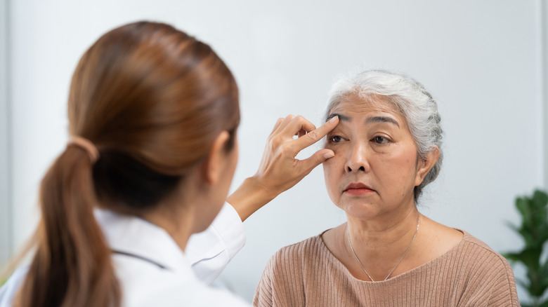 A young doctor examining an older patient's eye