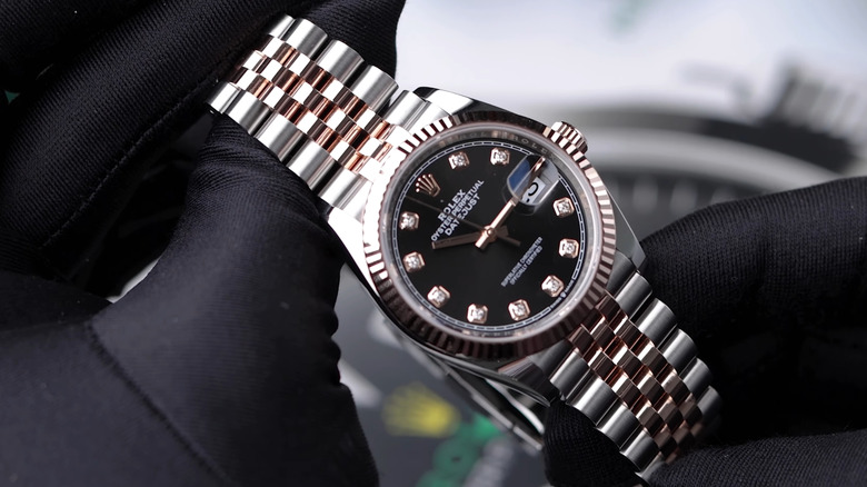 Closeup of a Rolex Datejust watch being held by gloved hands