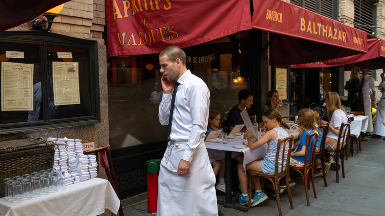 A waiter walks by customers at an outdoor table in New York.